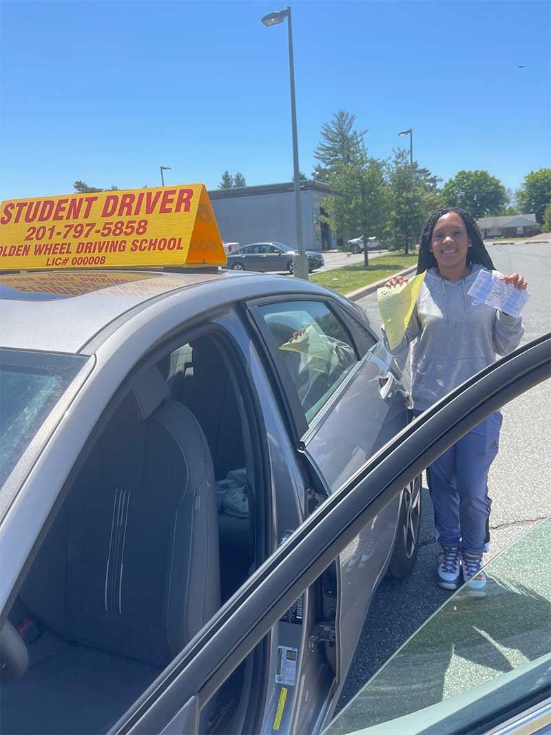Golden Wheel student with a passed road test beside the school car